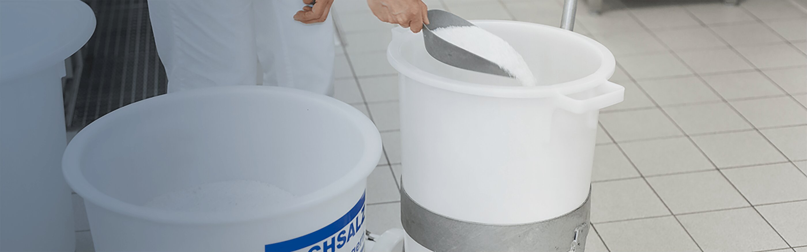 Round white container filled with salt, a scoop of salt is removed