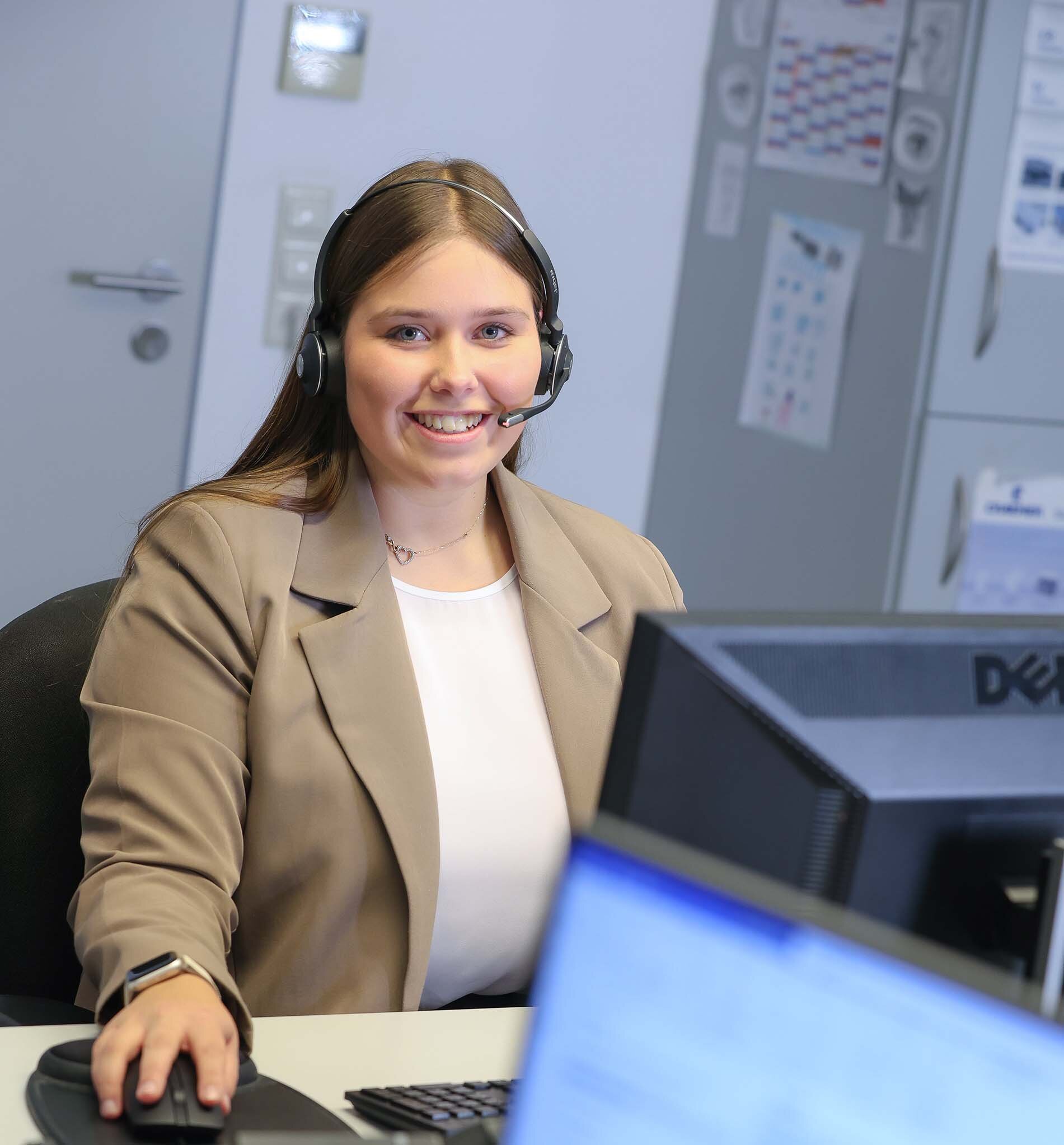 Duale Studentin mit Headset im Büro