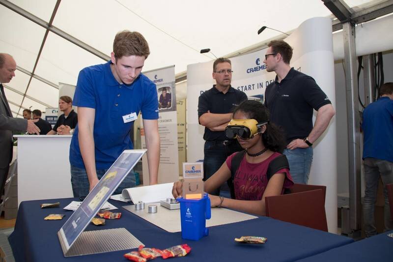 Azubi und experimentierende Schülerin am Stand