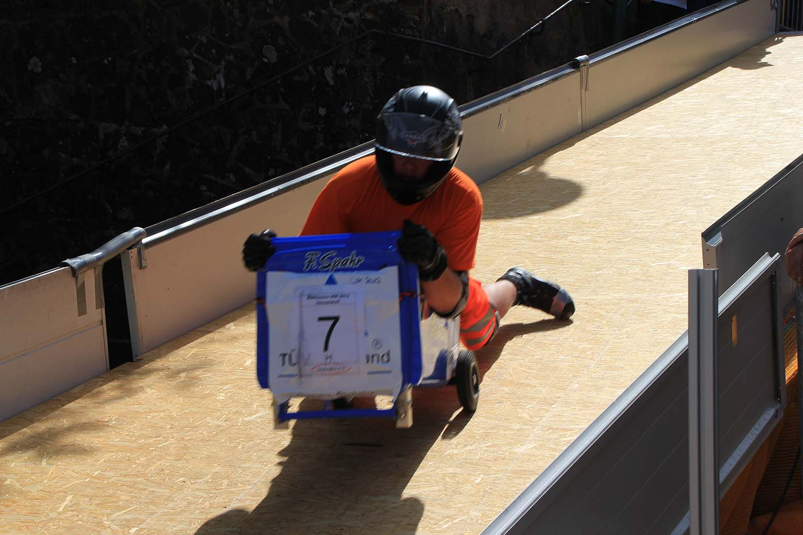 Person auf Mülltonne rollt die Piste hinab