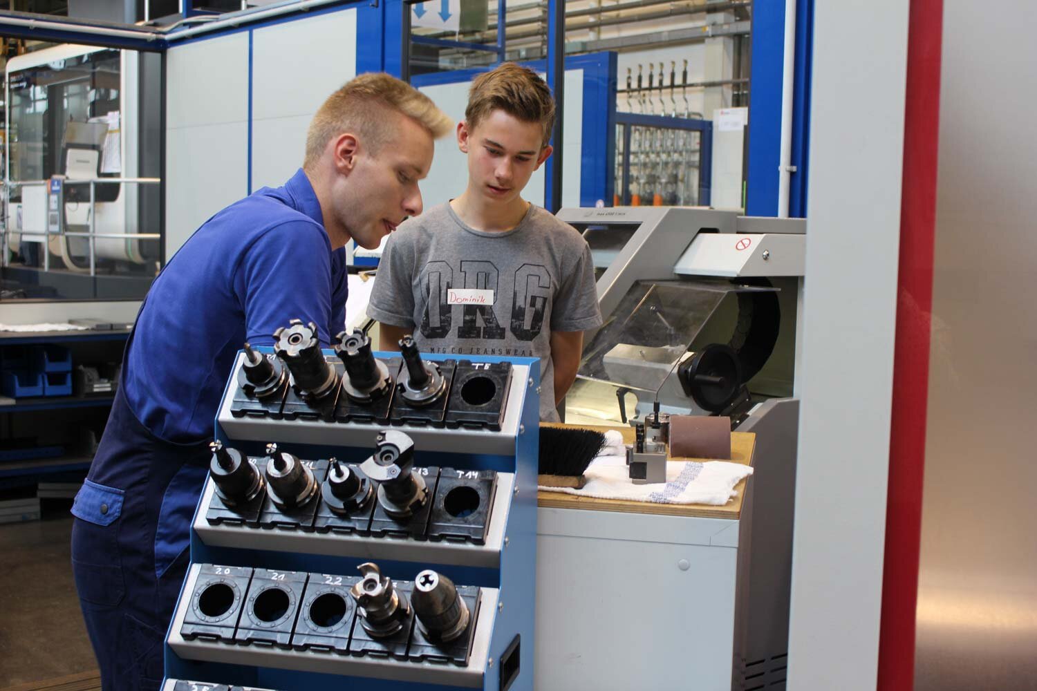 Auszubildender mit interessiertem Schüler an der CNC-Drehmaschine