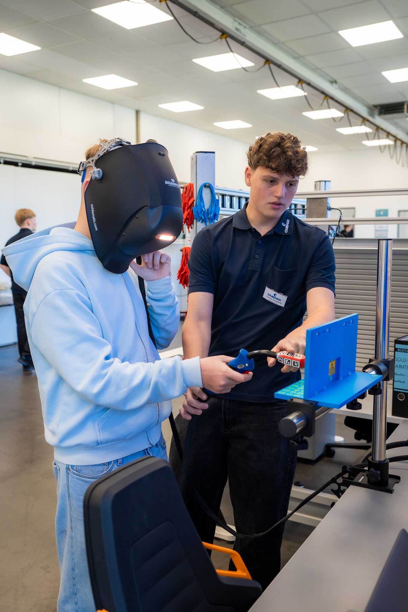 Schüler Sam Klüsener (1.v.r.) mit Schutzmaske und mit Thorben Greweling, Industriemechaniker-Azubi