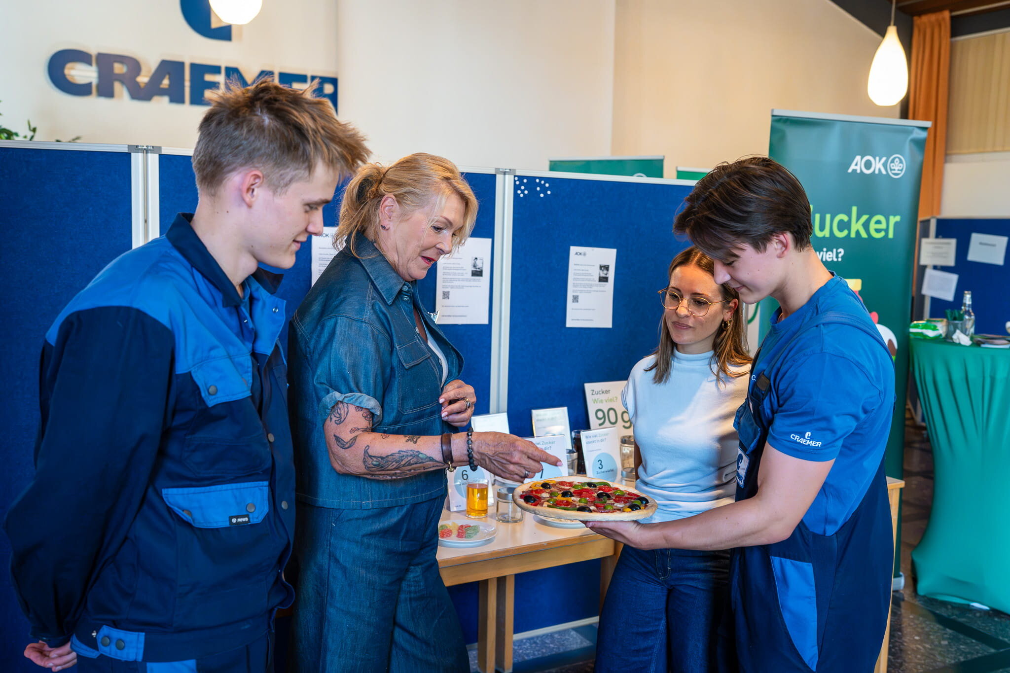 Am AOK-Stand erfahren Ben Heißmann (l.), Sarah Maltese und Constantin Kuhn von Susanne Dammann (2.v.r.), wie viel Zucker in alltäglichen Lebensmitteln enthalten ist.